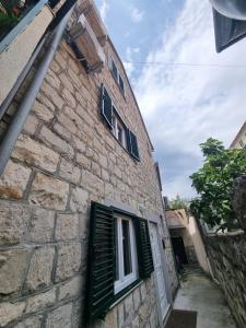 un edificio de piedra con persianas verdes y una ventana en Guesthouse Lion, en Split