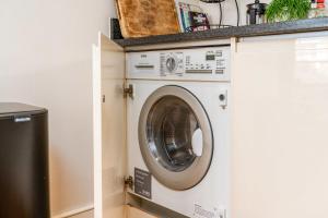 a washing machine in a kitchen with a counter at Bright & Spacious Battersea Flat in London