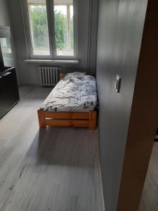 un piccolo letto in una camera con due finestre di mieszkanie w Giżycku a Giżycko