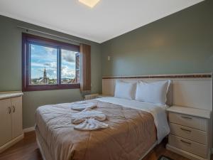 een slaapkamer met een groot bed en handdoeken bij Sierra Nevada - 501 in Gramado