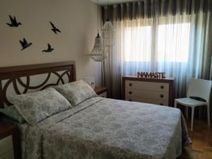 a bedroom with a bed and a dresser with birds on the wall at Ría del Burgo in Cambre