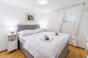 a bedroom with a large white bed with two towels on it at Apartmani P&S in Supetar