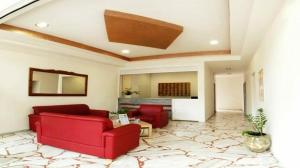 una sala de estar con 2 sofás rojos y una habitación con una alfombra grande en Zorbas Hotel, en Georgioupolis