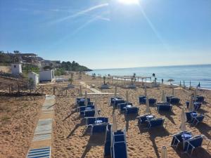 a beach with blue lounge chairs and the ocean at Villa Ida in Capo Rizzuto