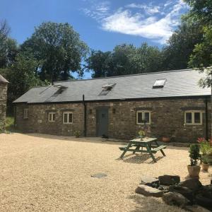 Llanwrda的住宿－Abercrymlyn barn，砖砌的建筑,前面设有野餐桌