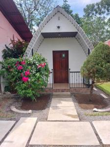 a small white house with a door and some flowers at Eco Hotel villas del Tortuguero 1 in Cariari