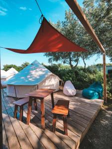 a yurt with two tables and chairs on a wooden deck at DOMO CAMP Sylt - Glamping Camp in Westerwall