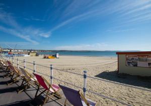 a row of chairs on a beach with the ocean at Bumble Bees in Weymouth