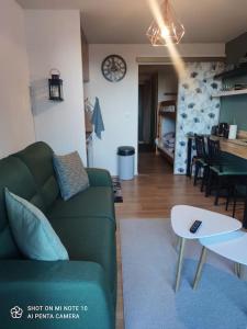 Beau studio cabine cozy في شامروس: غرفة معيشة مع أريكة خضراء وطاولة