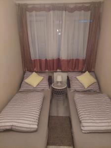 two beds in a small room with a window at Apartament L14, Mieszkanie dla Wszystkich in Konin