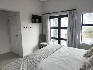 ランゲバーンにあるGolfers Haven Studio Apartmentの白いベッドルーム(ベッド1台、窓付)