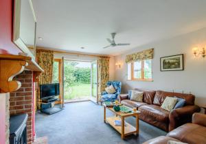 a living room with a couch and a tv at Brights Farm Lodge in Bramfield