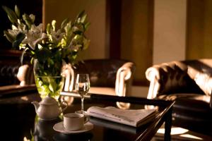 a table with a vase of flowers and a glass of wine at Valis Resort Hotel in Volos