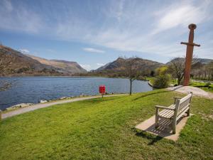 a bench sitting next to a cross next to a lake at Fir Tree Cottage in Caernarfon