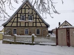 a house with a fence in the snow at Romantisches Rosencottage in Hofheim in Unterfranken