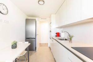 a kitchen with white cabinets and a stainless steel refrigerator at Piso climatizado y parking in Madrid