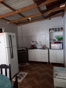 eine Küche mit weißen Schränken und einem Kühlschrank in der Unterkunft Casa temporada próximo à parque in Penha + 15 Fotos