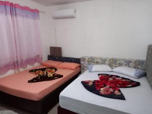 two beds in a room with flowers on them at Casa temporada próximo à parque in Penha