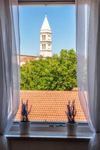 a window with a view of a clock tower at Apartmani P&S in Supetar