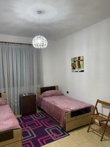 a bedroom with two beds and a chandelier at Dibra Home near City Center of Shkodra in Shkodër