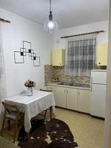 a kitchen with a white table and a sink and a table and chairs at Dibra Home near City Center of Shkodra in Shkodër