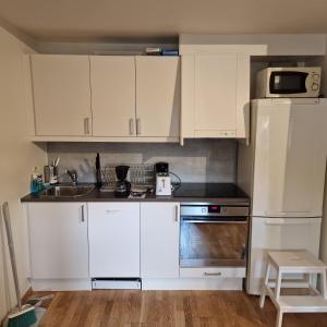 a kitchen with white cabinets and a sink and a microwave at Spacious 1 bedroom apartment in Lorenskog