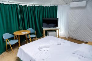 ナボダリにあるGlamping By The Seaのベッド、テレビ、テーブル、椅子が備わる客室です。