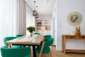 a dining room with a wooden table and green chairs at Sielsko Tu - Warmiński Port #13 in Olsztyn