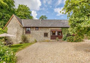 una casa de piedra con una entrada de grava delante de ella en Ash Cottage en Dulverton