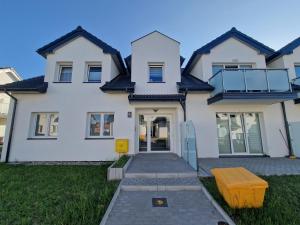 a white house with a yellow bench in front of it at Apartamenty Malaga in Darłowo