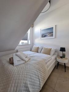 a white bedroom with a bed and a window at Apartamenty Malaga in Darłowo