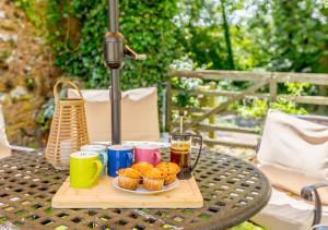 una mesa con una bandeja de cupcakes y bebidas. en Ash Cottage, en Dulverton