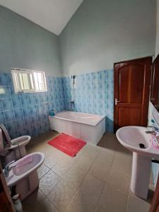 ein Badezimmer mit einer Badewanne, einem WC und einem Waschbecken in der Unterkunft illémi Guest house in Abomey-Calavi