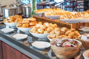 a buffet filled with different types of bread and pastries at Castelmar Hotel in Florianópolis +34 photos