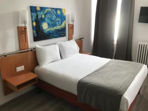 1 dormitorio con 1 cama y una pintura en la pared en Hotel Morand, en Rouen