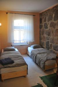 two beds in a room with a stone wall at Apartment Battin 44 Uckermark in Brüssow
