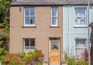 a brick house with a yellow door and windows at The Nook in Beaumaris