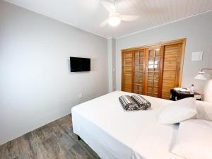 a white bedroom with a bed and a television at Pousada Ar da Montanha in Serra Negra