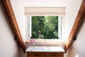 een raam in een kamer met een vaas met bloemen op een tafel bij Fantastisch familiehuis met grote tuin I Bosrijk in Lunteren