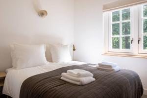 a bedroom with a bed with white towels on it at Fantastisch familiehuis met grote tuin I Bosrijk in Lunteren +35 photos