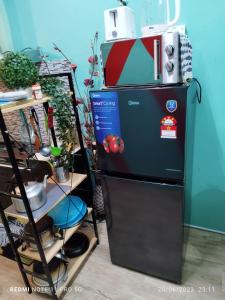 um frigorífico ao lado de uma prateleira com panelas e frigideiras em Basrie Homestay Pagoh - Private Pool/W-ifi/NetFlix/Cozy em Pagoh