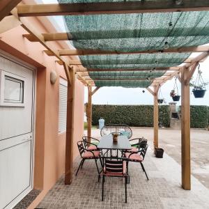 un patio con mesa y sillas bajo una pérgola en O POSTIGO, en Praia da Vitória