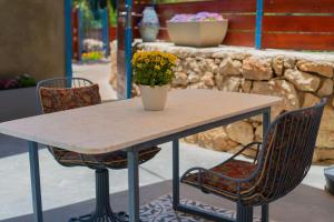 a table with two chairs and a vase with flowers on it at פרלה צימרים in Jerusalem