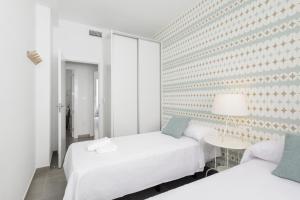 Habitación blanca con 2 camas y mesa en HI ROOM - Smart Apartments - HE 2, en Granada