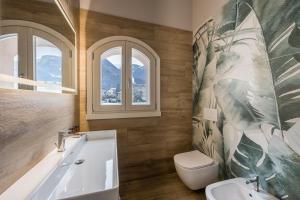 a bathroom with a tub and a toilet and windows at Bianco Hotel in Primaluna