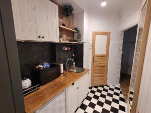 eine Küche mit weißen Schränken, einer Spüle und einem karierten Boden in der Unterkunft Smulik Flat 21 in Warschau