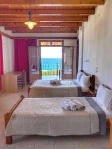 two beds in a room with a view of the ocean at XENIA HOTEL in Sfakia