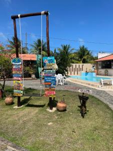 a bunch of signs on a pole in the grass at Pousada Kaluanã in Japaratinga