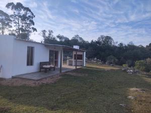 una pequeña casa blanca con un banco en un patio en Las Carobas en Minas