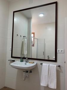 a bathroom with a white sink and a large mirror at Casa de campo "La Campanera" in Constantina